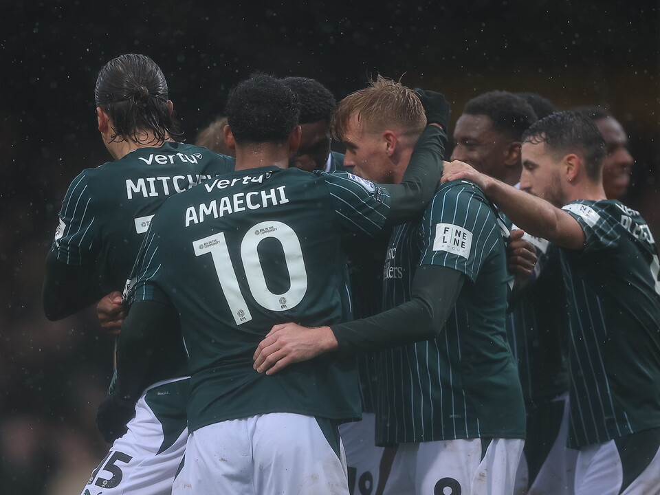 Players wearing green and white jerseys huddle in celebration; one wears number 10.