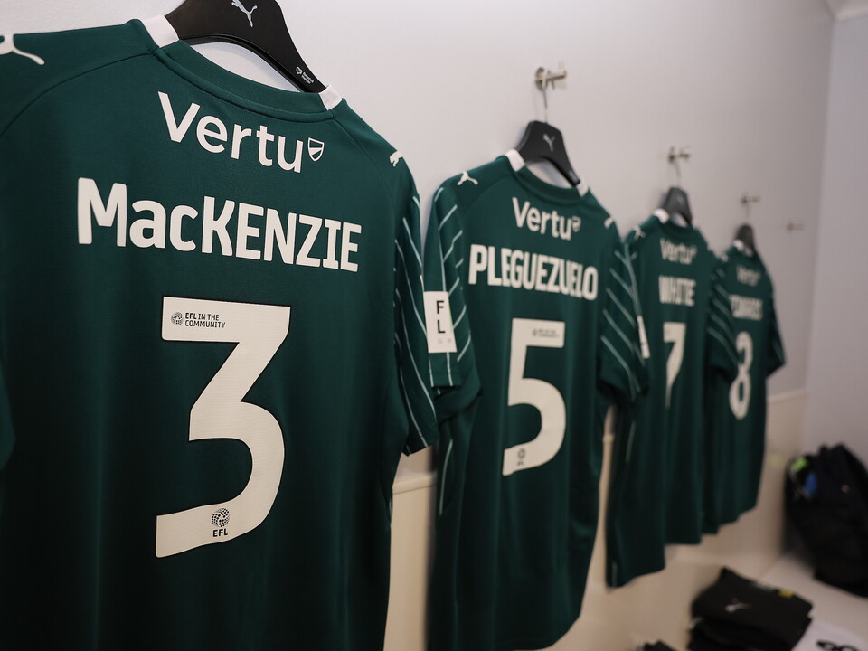 Green football shirts with the numbers 3, 5, 7, and 3 hanging on a wall.
