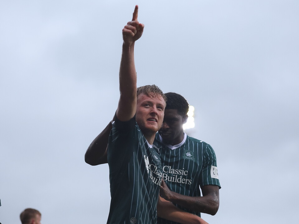 Footballer pointing at sky with teammate behind him.