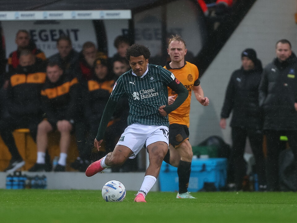 Football player in green shirt and white shorts kicks the ball in a game