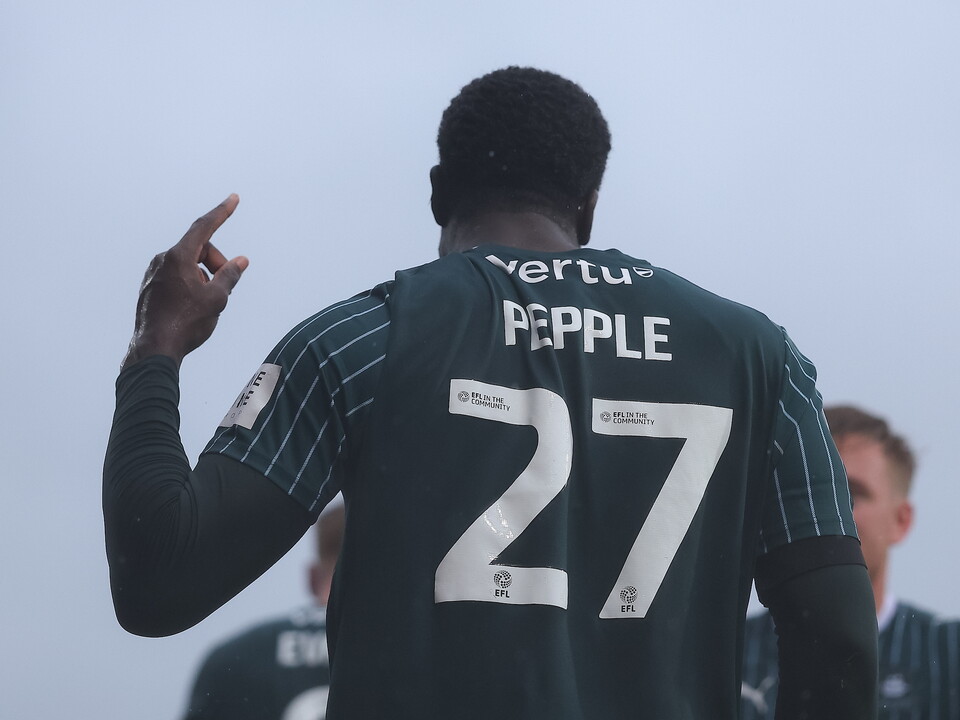 Soccer player number 27 walking on pitch, back view, wearing green shirt.
