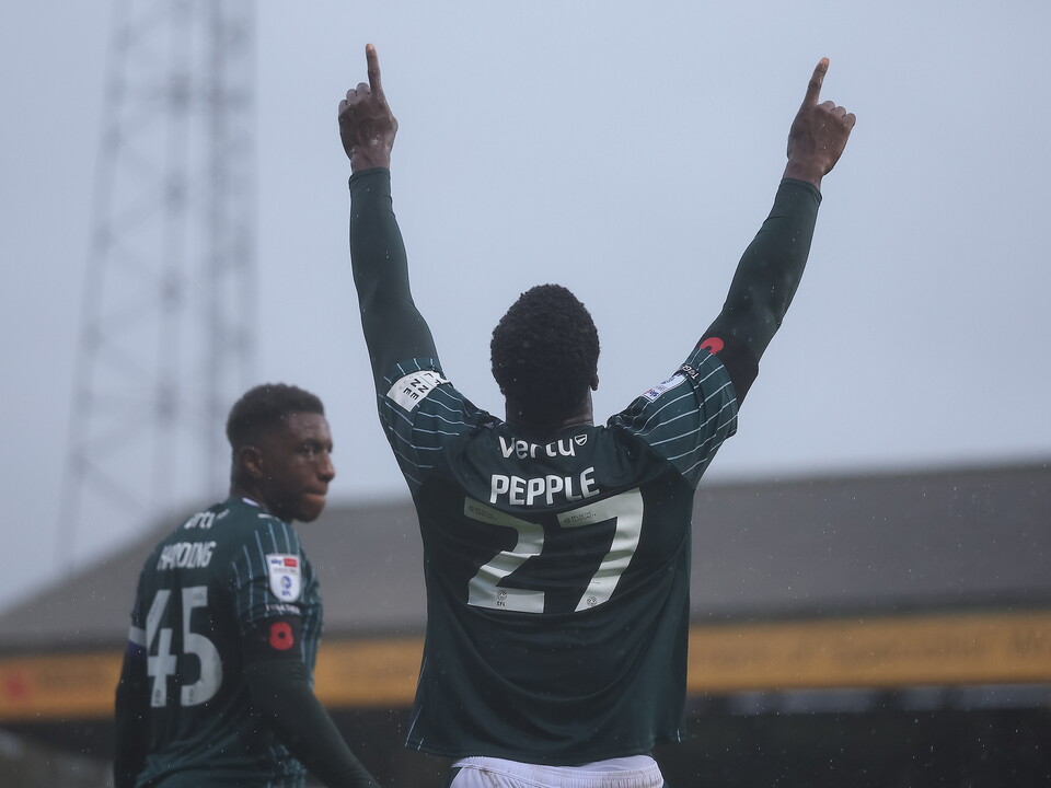 Two football players celebrating, one with raised hands wearing a green jersey with the number 27.