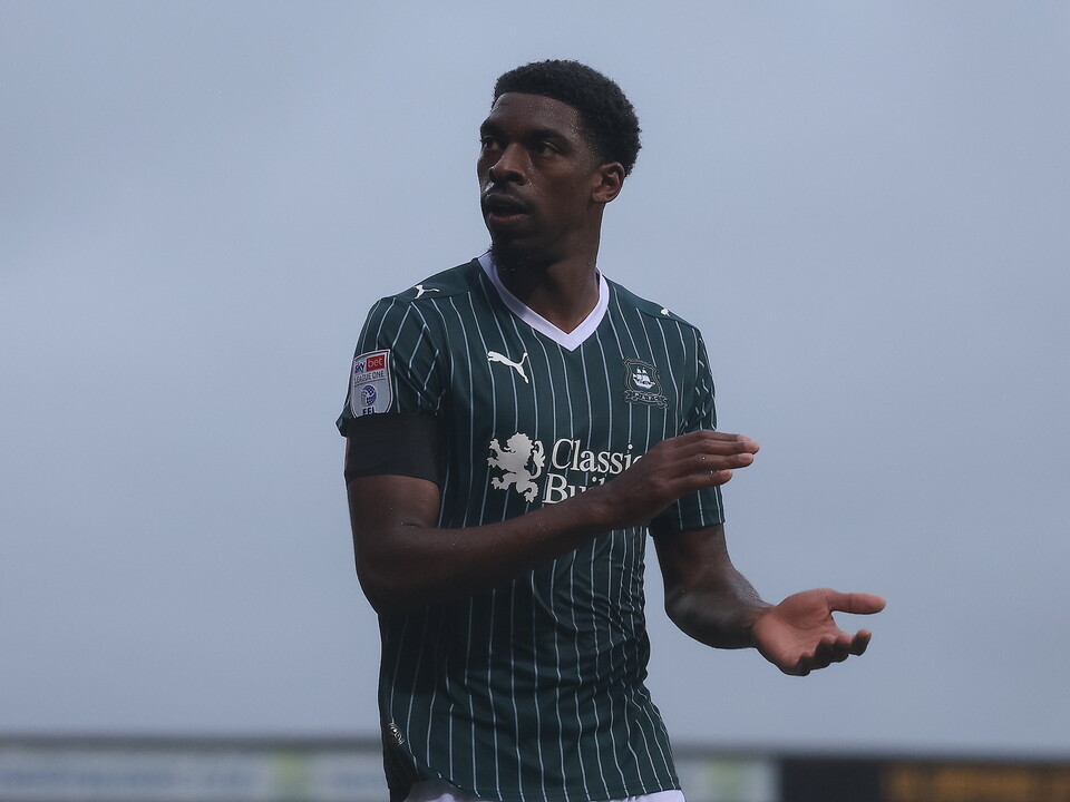 Footballer in green-and-white striped shirt with hands open and palms facing up.