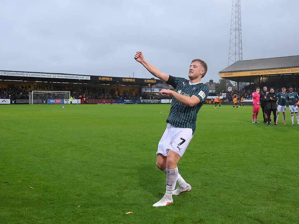 Player number 7 celebrates on a football pitch under a cloudy sky.
