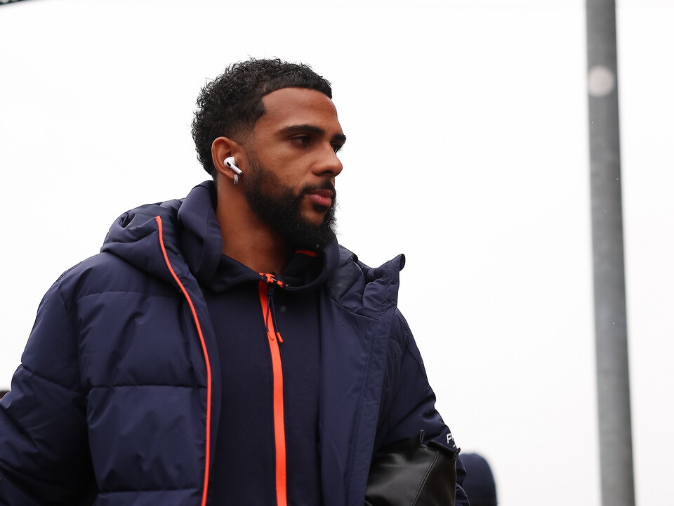 Man with beard in navy puffer jacket and earphones