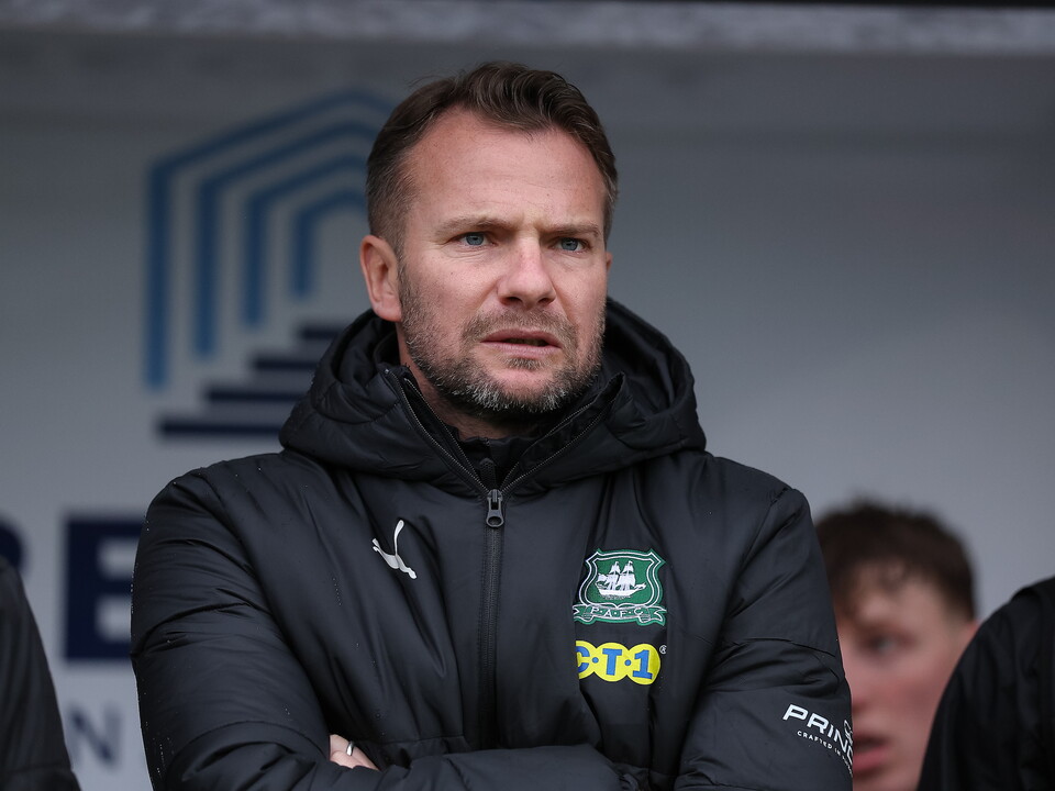 Manager with arms folded, wearing a black hooded jacket and looking serious