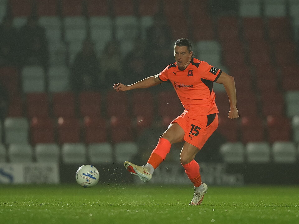 Footballer in orange uniform, kicking a white and black soccer ball, number 15.