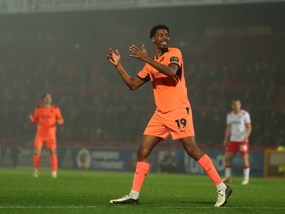 Footballer wearing orange kit with 19 on back celebrates on pitch.