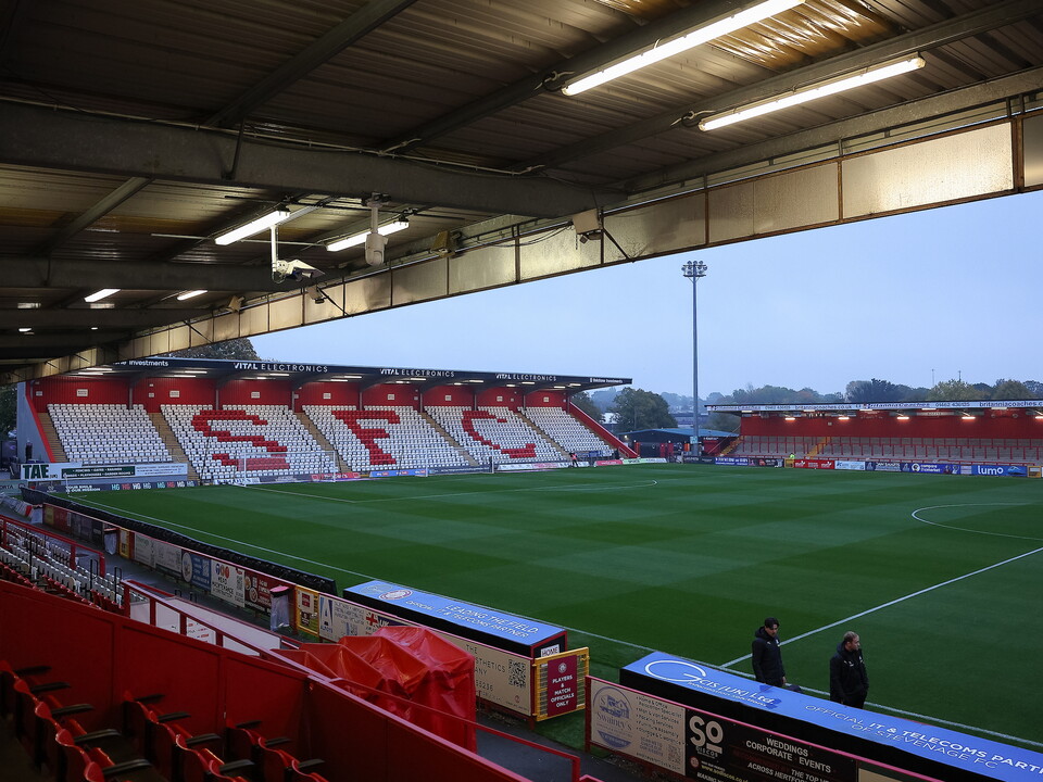 Empty stadium with red seats and green pitch