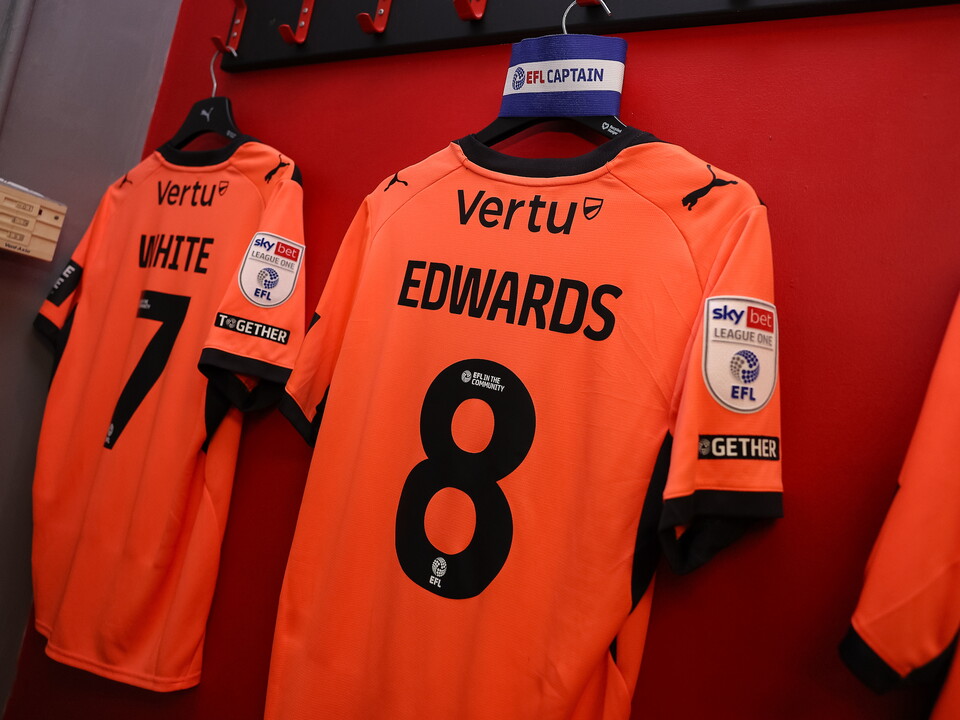 Orange shirts hanging on a wall with the number 7 and the name Edwards