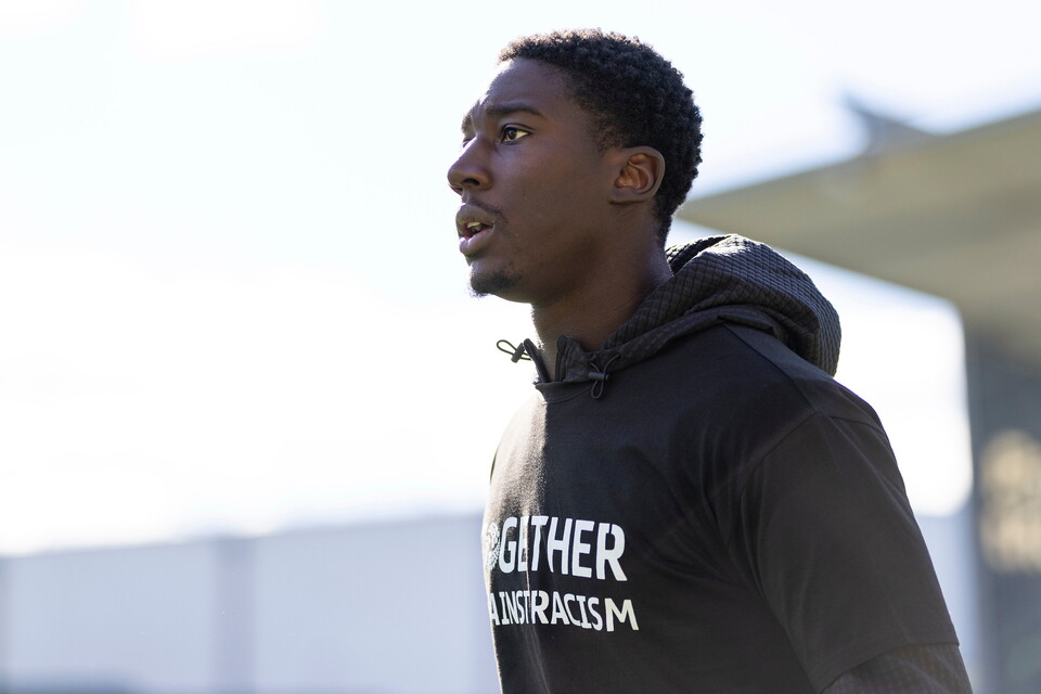 A man in a black hoodie with white writing saying Together Over Racism.
