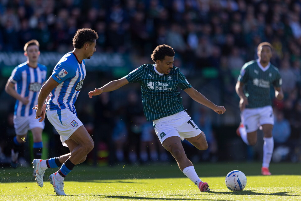Two players compete for a ball on a football pitch during a match.