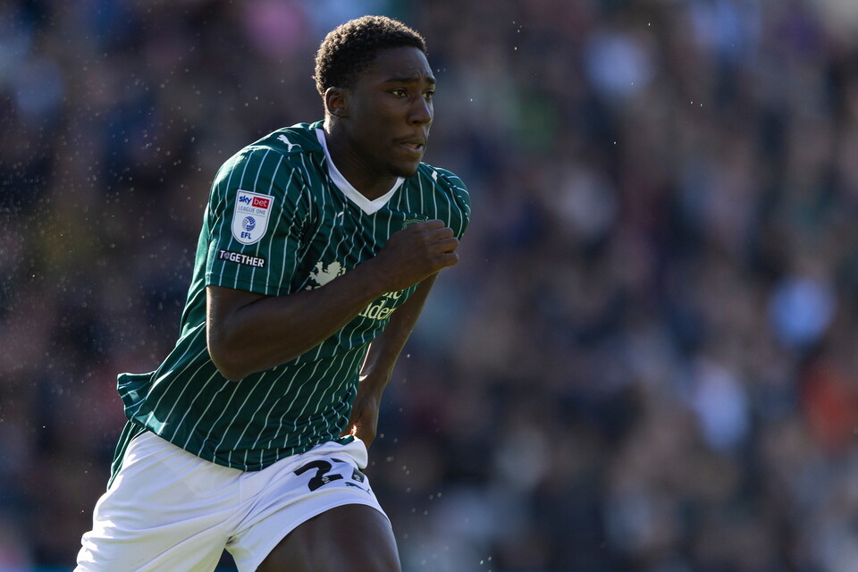 Footballer running with hands on hips wearing green and white strip