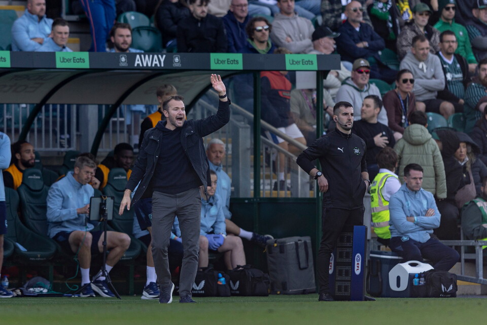 Coach signals to players on sideline during a football match.