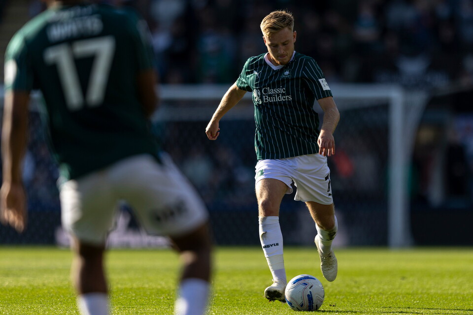 Football player wearing green shirt with number 17 on back kicks ball during match