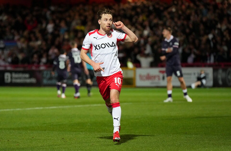 A football player wearing a white and red shirt with XIOM on it celebrates.