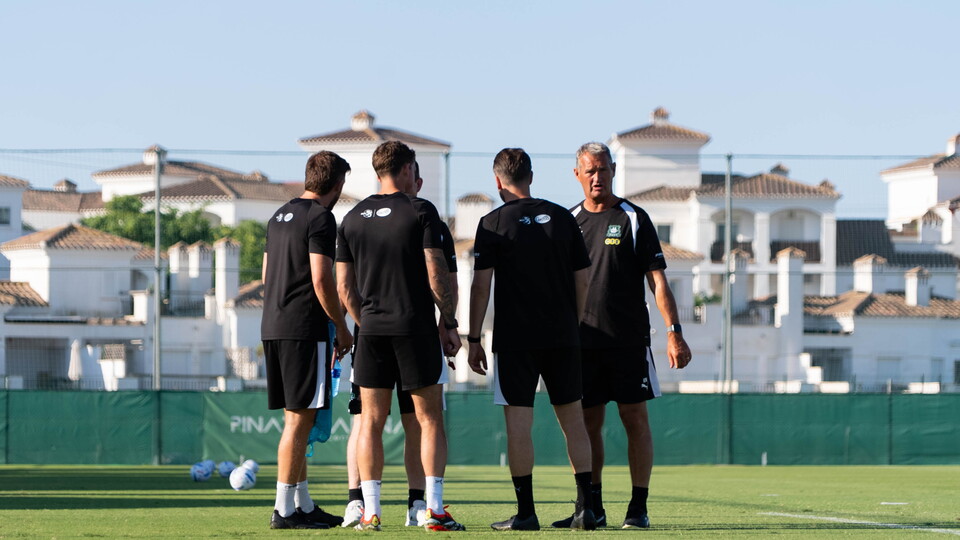 Argyle coaches stand together in the sun in Spain.
