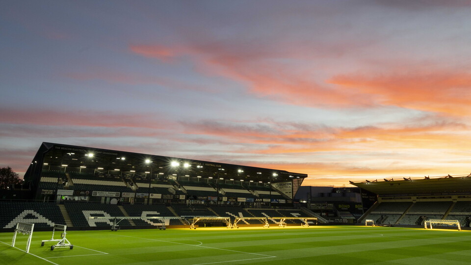 An empty football stadium with the sunset in the background